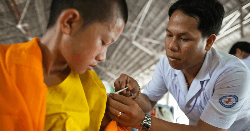 Young monk receives vaccination from medical professional promoting pediatric healthcare and elimination of disorders