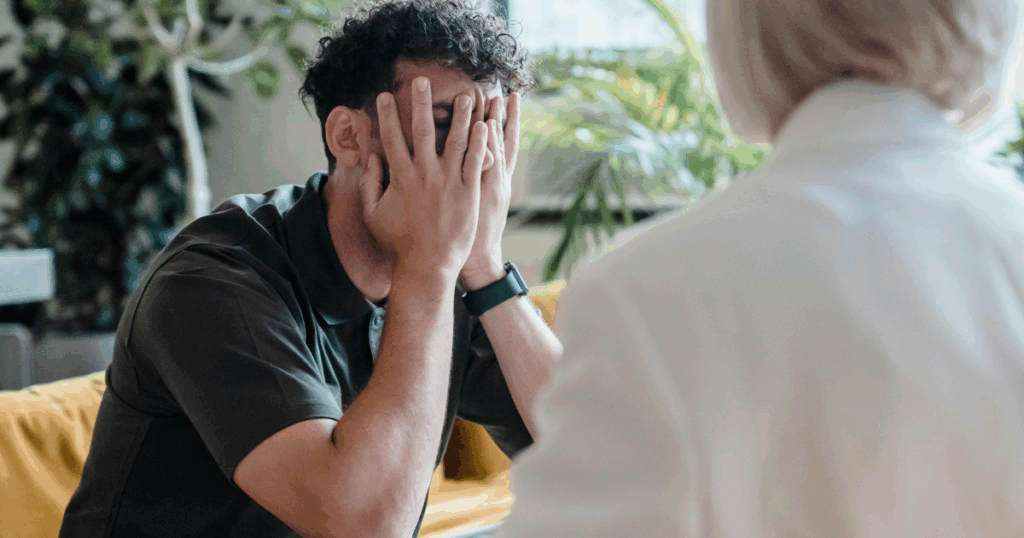 Man covering face in therapy session Mental health image for Ganser Syndrome information showing stress and support