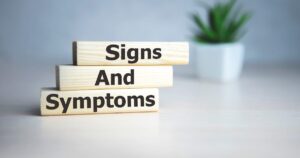Wooden blocks stacked to read Signs And Symptoms on a light desk signaling a medical topic
