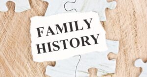 Torn white card reading FAMILY HISTORY laid on a wooden puzzle piece background