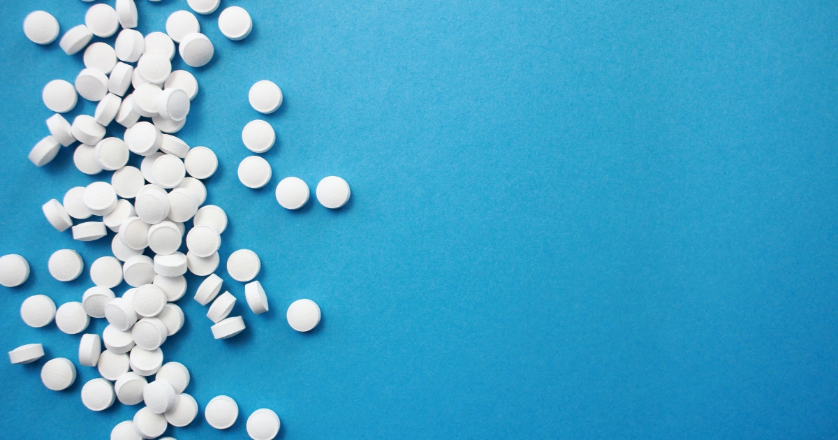 White tablets scattered on a blue surface near the left edge