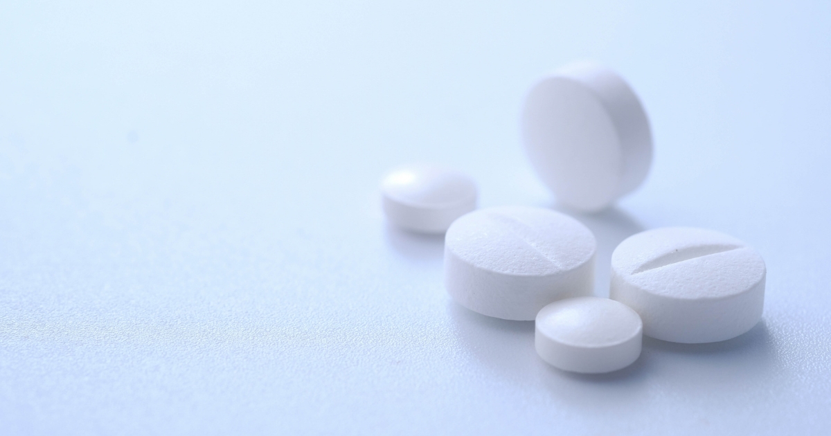White round tablets scattered on a pale blue surface on a soft background