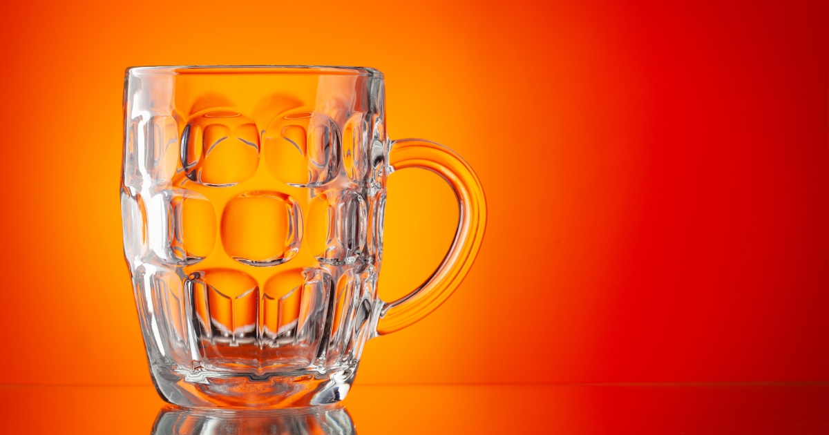 Clear glass mug with a faceted bubble like pattern against an orange gradient background