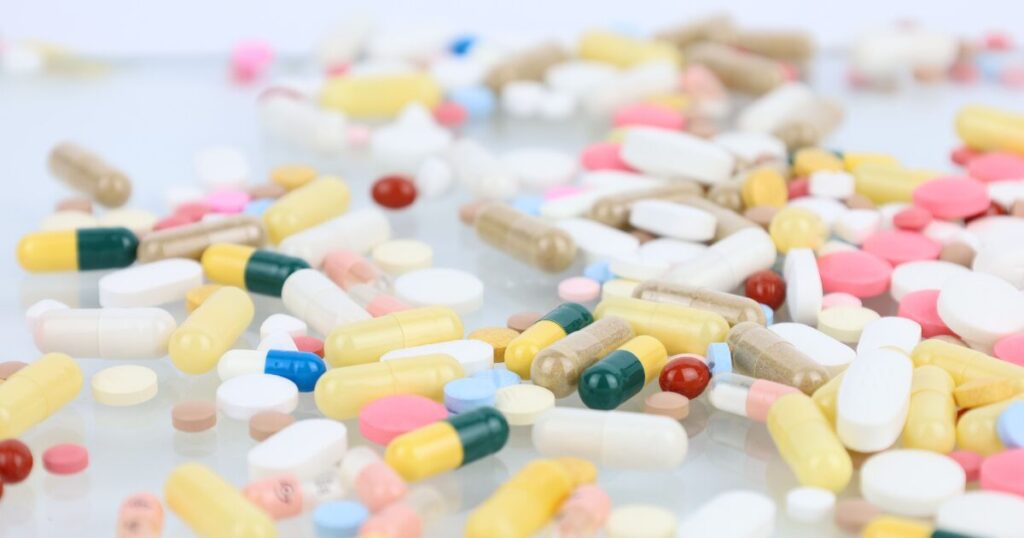 Assorted pills and capsules scattered on a reflective surface